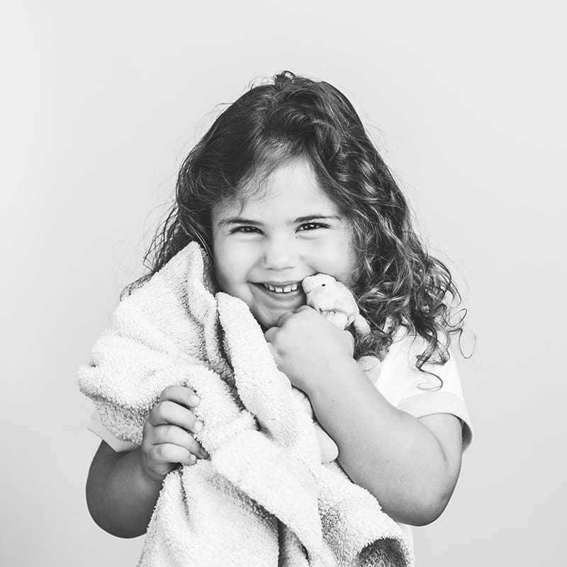 little kid holding blanket smiling for black and white personality photo